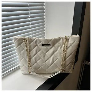 Macro shot of cream quilted tote bag with diamond pattern and gold chain strap detail