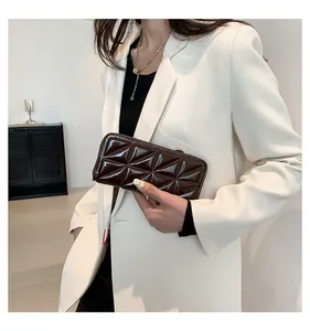 Vue détaillée de la texture géométrique sur cette pochette en cuir verni brillant