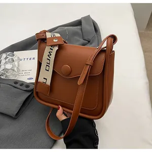 Dettaglio della borsa a tracolla in pelle PU marrone con doppie spalline su sfondo grigio