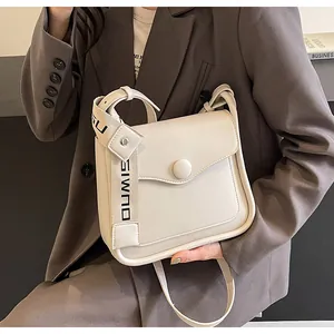 Detail of cream white crossbody bag with stylish letter strap and round buckle closure