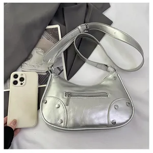 Detail view of silver rivet dumpling bag with smartphone for size reference