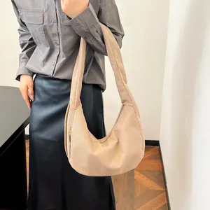 Beige corduroy crescent shoulder bag with drawstring detail worn by a model in casual style