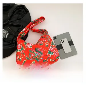 Detailed top view of ethnic floral tote bag with smartphone and tablet on white desk