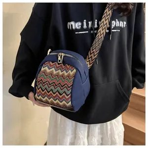 Detail of ethnic canvas crossbody bag featuring colorful wave patterns and golden zippers