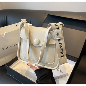 Detail of cream flap crossbody bag with wide logo strap and premium gift box