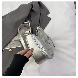 Detail view of silver metallic dumpling bag featuring punk rivets and motor style zipper