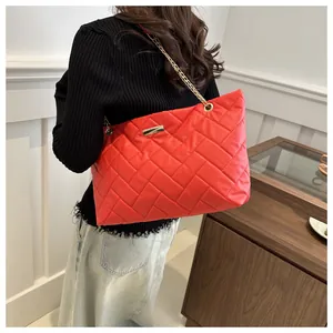 Detail of red quilted tote bag with gold chain strap and elegant chevron stitching pattern