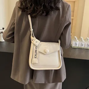 Borsa a tracolla chic in vernice beige con ampia tracolla a lettere su una modella