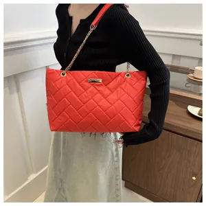Close-up of a large red quilted tote bag with golden hardware and chain strap accents