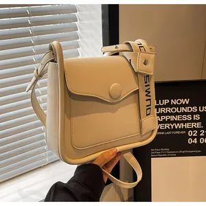 Detail of cream crossbody bag showing the woven shoulder strap with black DUMIS lettering