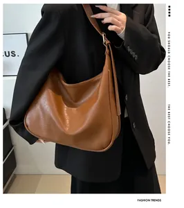 Brown faux leather hobo shoulder bag with wide strap styled on a model in a black suit