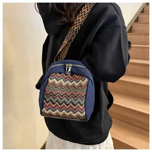 Detail of navy canvas crossbody bag with ethnic pattern strap and golden dual zippers