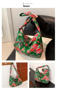 Close-up of green tote bag with traditional red peony floral patterns and silky texture