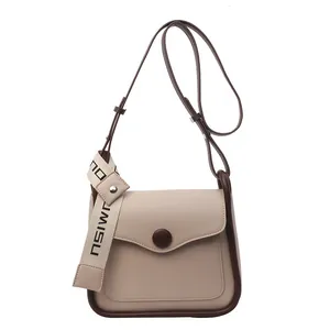 Chic beige crossbody bag with wave flap and contrast brown trim on white background