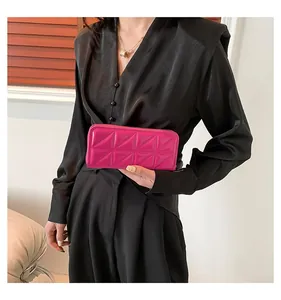 Détail du portefeuille matelassé en cuir verni rose fuchsia avec fermeture éclair tenue