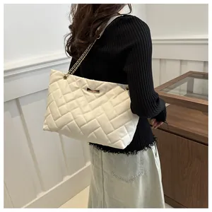 Detail view of white quilted shoulder bag with metal chain strap and elegant rhombus pattern