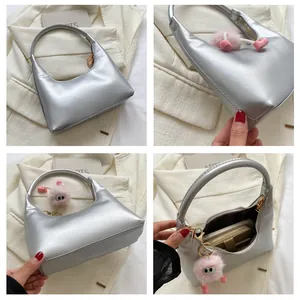 Dettaglio borsa a mezzaluna argento con ciondolo di peluche rosa e scomparto interno