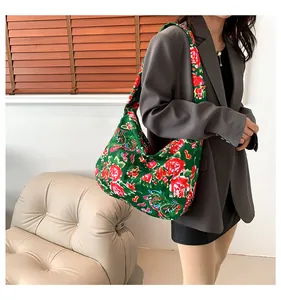 Close-up of traditional peony floral pattern on a green ethnic tote bag shown on shoulder