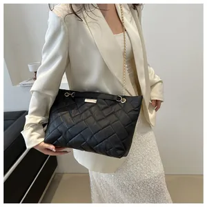 Detail of black quilted shoulder bag with woven leather texture and gold chain strap