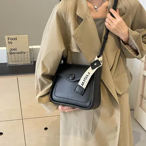 Minimalist black leather crossbody square bag with MISU branded strap and round buckle