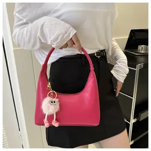 Dettaglio borsa hobo fucsia con ciondolo mostro di peluche indossata da una modella