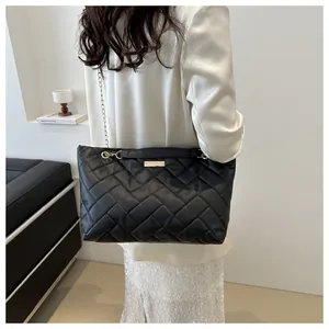 Close-up of black quilted tote bag featuring a gold chain strap and soft woven texture
