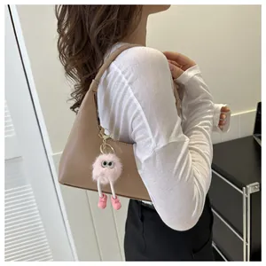 Dettaglio borsa hobo kaki con un ciondolo di peluche rosa sulla tracolla