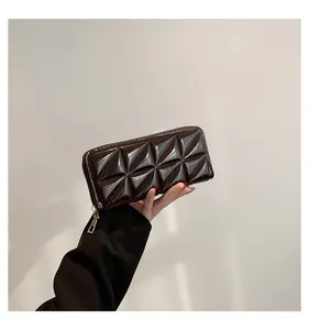 Détail d'un portefeuille marron foncé à motif prisme avec une fermeture dorée