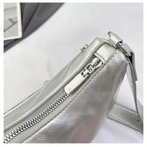 Detail of silver metallic textured crossbody bag showing zipper and stitching