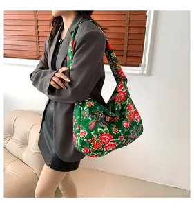 Close-up of ethnic tote bag with red peony floral pattern on a green fabric background