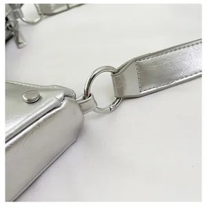 Close-up of metallic silver pleated bag with polished ring link and rivet details