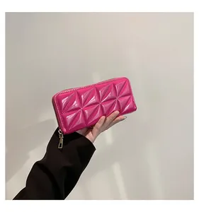 Détail d'un sac à main rose brillant avec texture gaufrée géométrique et zip métallique doré