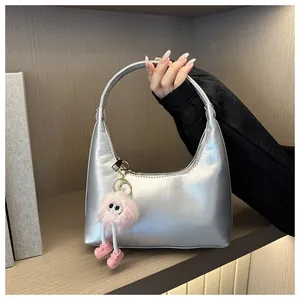 Dettaglio borsa hobo argento metallizzato con ciondolo in peluche e cerniera elegante