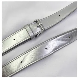 Detail shot of silver metallic leather belt with rivet texture and pin buckle closure