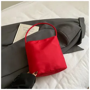 Detail of red satin handbag with slim handle placed on a grey blazer and book