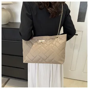 Detail of beige quilted tote bag featuring diamond pattern and gold chain strap