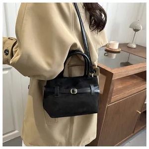 Détail du sac seau noir en daim mat avec bandoulière en cuir et boucle métallique