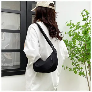 Minimalist black crescent crossbody bag with adjustable strap worn in a lifestyle setting