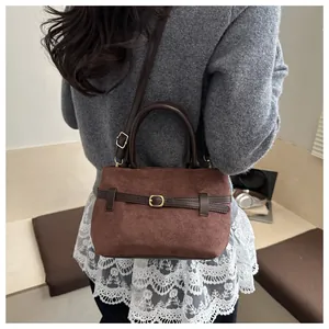 Gros plan sur un sac seau vintage en daim marron avec boucle de ceinture et bandoulière