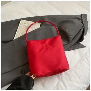 Close-up of red canvas handbag featuring Hope and Future embroidery on a grey blazer