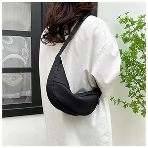 Detailed back view of a minimalist black crescent nylon crossbody bag on a model