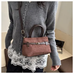 Détail du sac seau en daim marron avec boucle de ceinture et finitions dorées chic