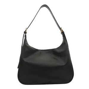Minimalist black PU leather hobo shoulder bag with golden rings on white background