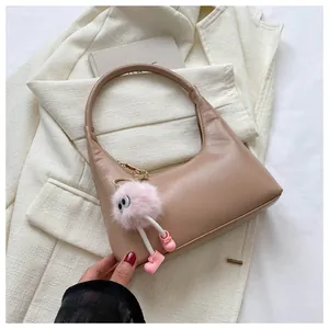 Borsa hobo marrone in ecopelle con ciondolo mostro di peluche rosa su blazer bianco