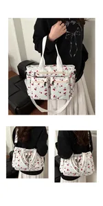 Detail showing multiple zipper pockets and cherry print on white canvas tote bag