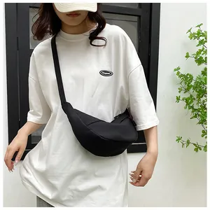 Model wearing a minimalist black nylon crescent crossbody bag with adjustable strap
