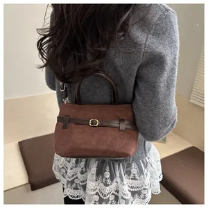 Détail du sac seau vintage en daim marron foncé avec boucle de ceinture et sangle