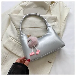Dettaglio borsa hobo metallizzata argento su blazer bianco con ciondolo peluche rosa