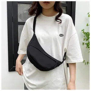 Close-up of a black nylon crescent bag with adjustable wide strap on a white shirt