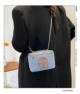 Detail einer hellblauen Umhängetasche in Denim-Optik mit goldenem Doppelreißverschluss